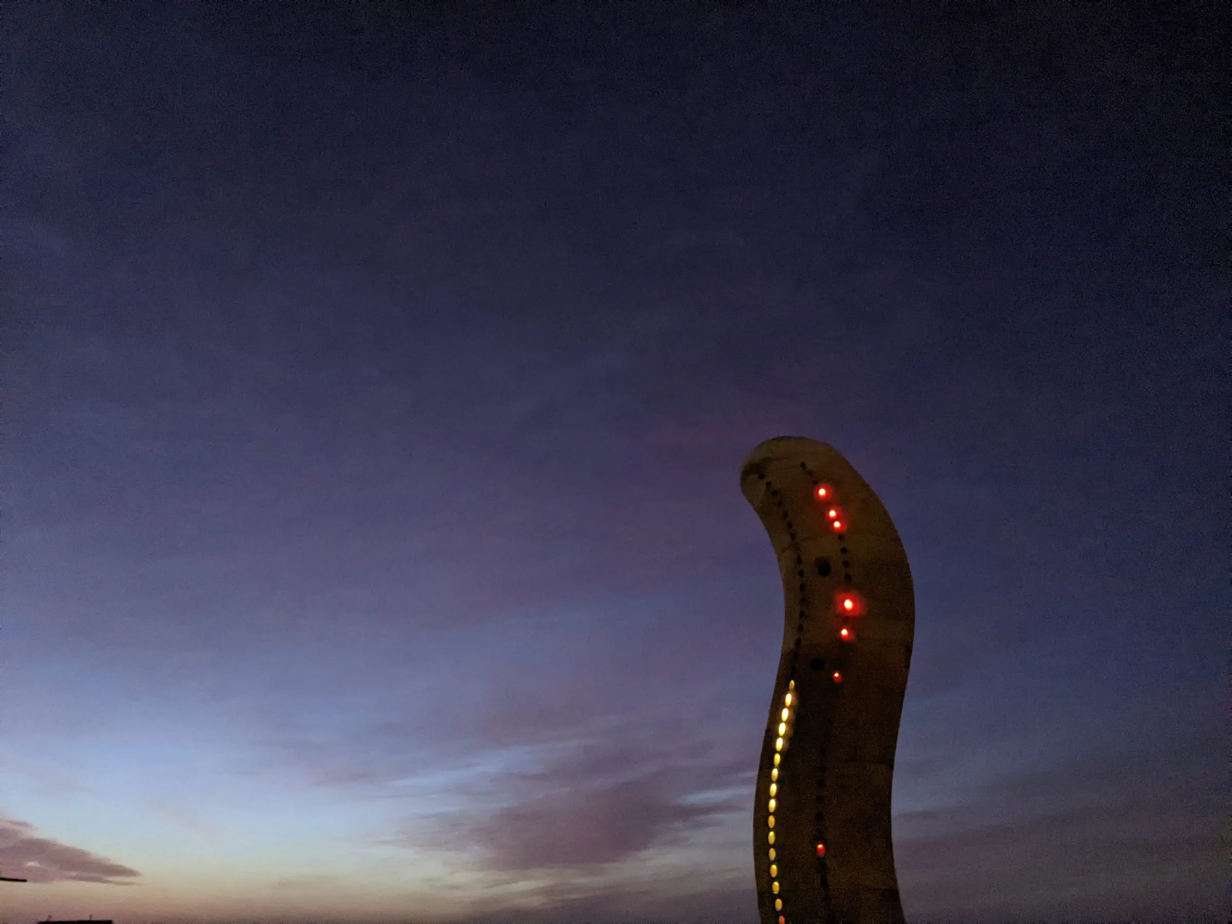 The sculpture at night, its light spilling onto the sand