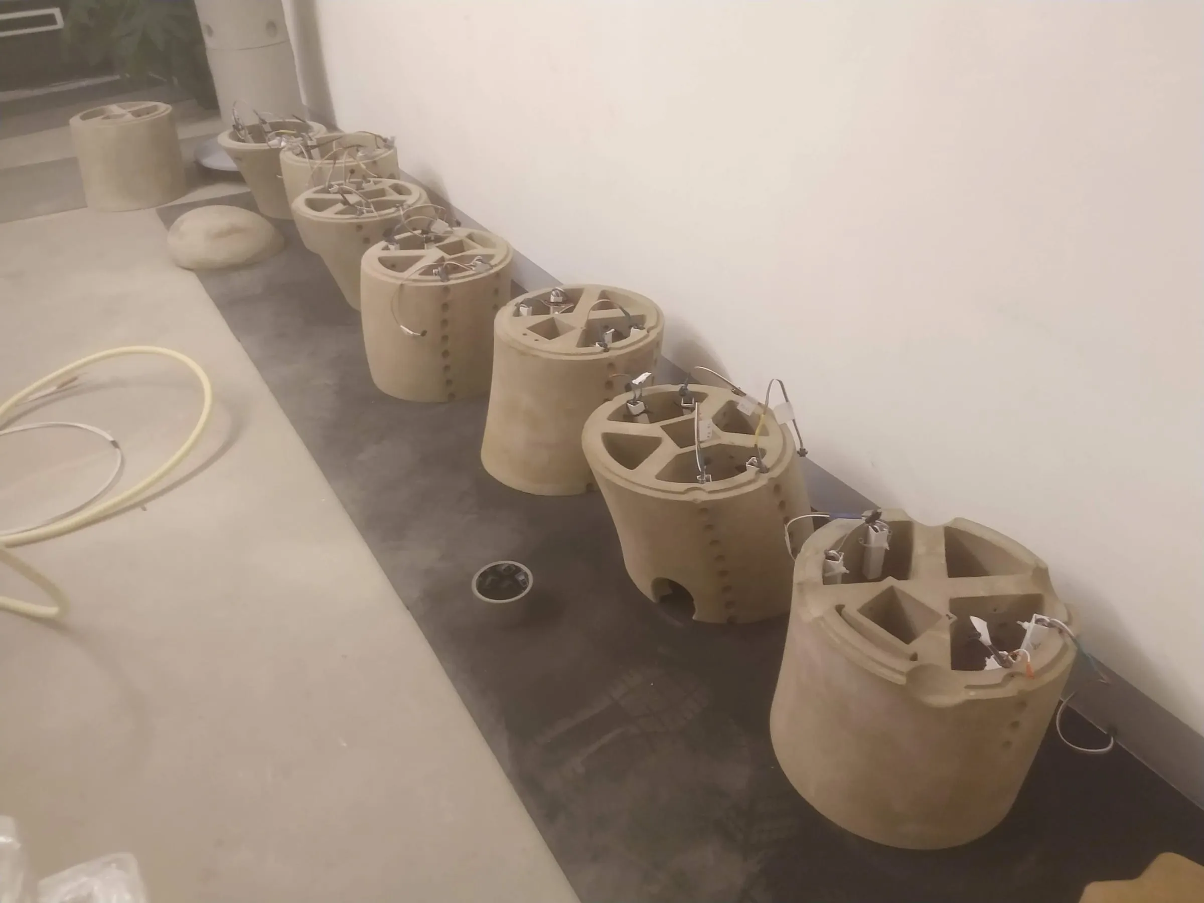 Sand-printed segments lined up on the floor with internal bracing and wiring